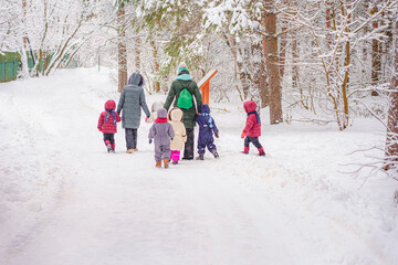 Fototapeta na wymiar Children walk of children with teachers in nature on winter day