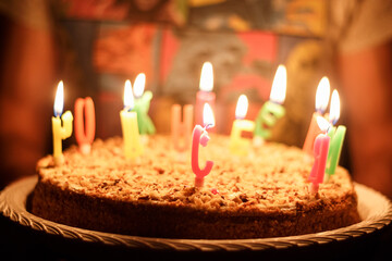 Festive cake with burning candles on the hands of a person close-up, holiday, birthday.