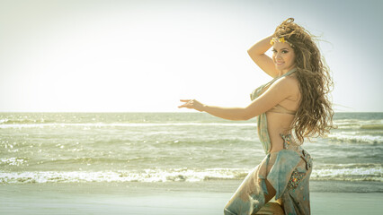 A bellydance dancer dancing to arabic music in front of a beach