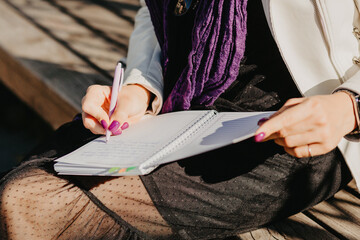 Young girl writes in a notebook with a pen