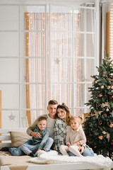 The father, mother holds little son and daughter near Christmas tree. Happy New Year and Merry Christmas. Christmas decorated interior. The concept of family holiday. upper half. Close up.
