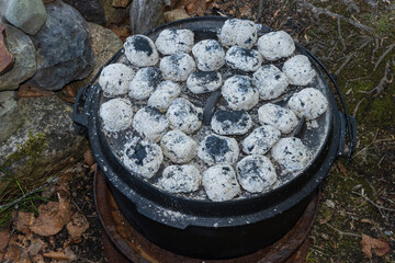 Aerial view to charcoal briquettes on top a cast iron dutch oven.