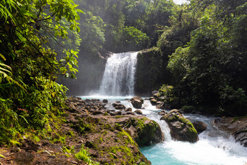 Fototapeta na wymiar Waterfall and blue river containing minerals in costa rica rainforest.