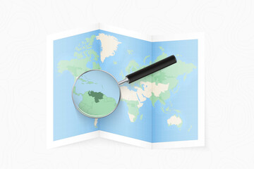 Fototapeta premium Enlarge Venezuela with a magnifying glass on a folded map of the world.