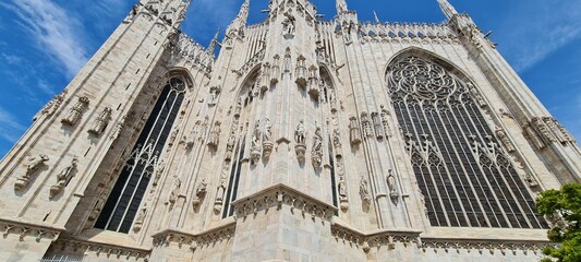 Naklejka premium Cathedral Duomo di Milano. Panoramic view of the ornate facade with many marble sculptures on the wall. Back view of the cathedral of European country. Detail of a building.