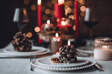 Rustic table decor for Christmas or New Year family dinner. Centrepiece with red candle, dry orange, cone, cinnamon, anise. Zero waste eco-friendly home. Cozy atmosphere, dark background. Close up