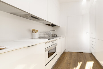 Kitchen of plain white furniture with minimalist design and integrated appliances of the same color