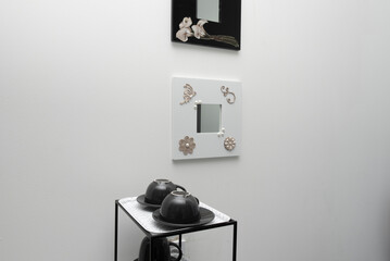 Black metal side table with matching teacups and decorative mirrors on the wall