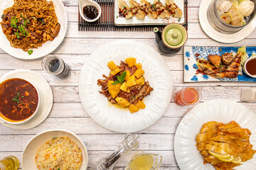 Set of asian cuisine dishes with orange duck, fried gyozas, wok stir fry noodles, lemon chicken, rolls with sauce