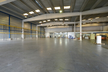 Empty interior of an industrial warehouse with polished concrete floors and concrete ribs supporting the ceiling