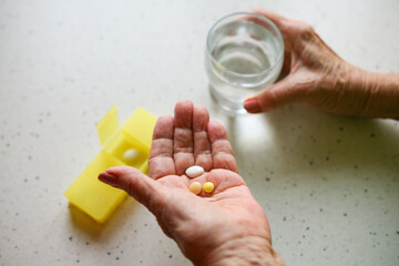 Taking medication - close-up of an elderly person's hand with pills - obrazy, fototapety, plakaty