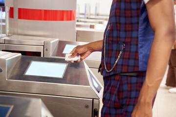 unrecognizable man passing the entrance ticket to a subway station