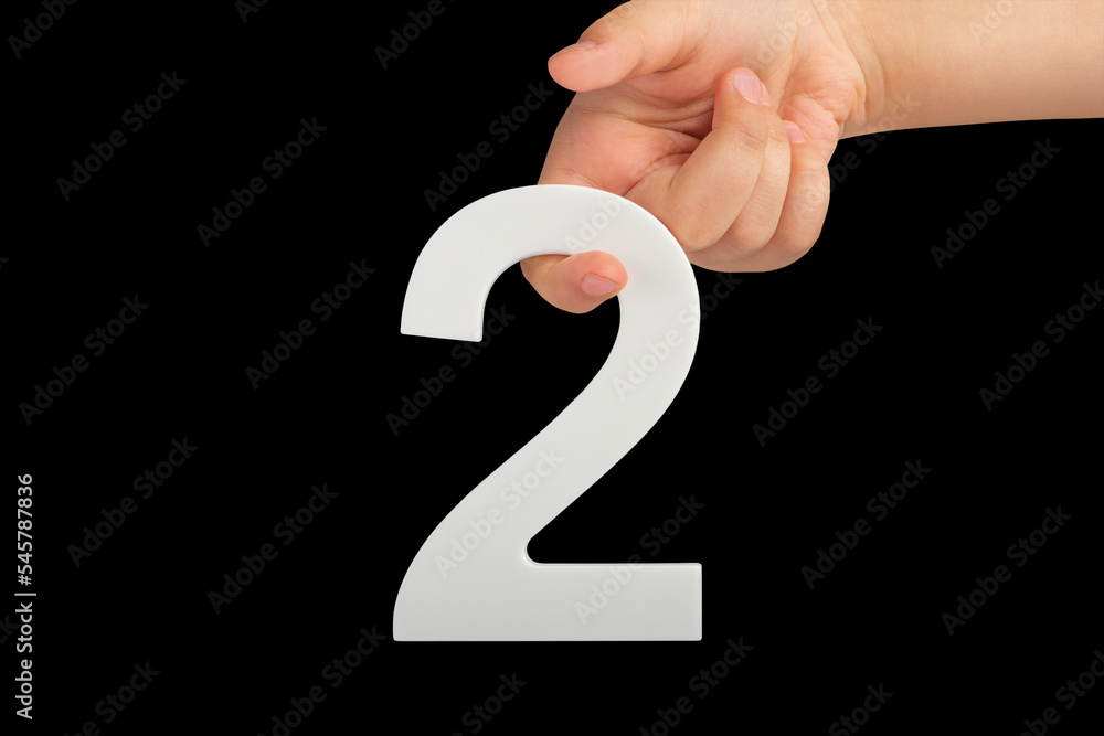 Leinwandbilder number two in hand isolated on black background. number two white in a child's hand on a black backg