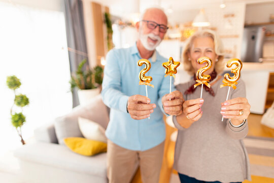 Senior couple holding numbers 2023 for New Year home party