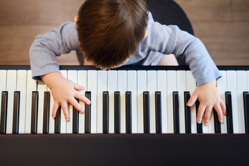 Toddler baby plays piano in home living room, music lessons. Happy child boy learns to play music on an electric piano. Kid boy age one year four months © Андрей Журавлев