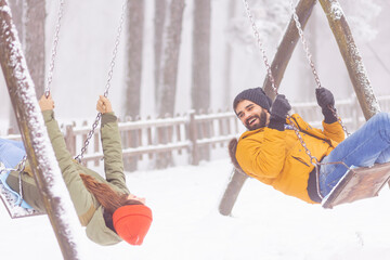 Couple playing on an outdoor swing set while on winter vacation