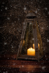 Old rusty lantarn. with a burning candle inside. during  beginning snowfall