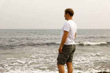 Fototapeta na wymiar A young handsome man walks by the sea, the concept of a healthy lifestyle