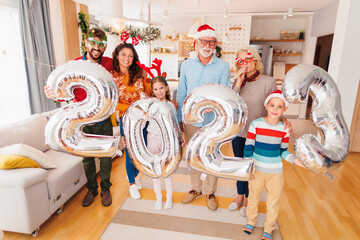Family holding balloons shaped as numbers 2023 representing the upcoming New Year