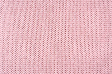 Close up background of knitted wool fabric made of viscose yarn. Pastel pink color wool knitwear...