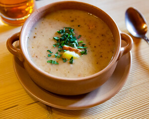 Traditional Polish sour soup zurek thickened with sourdough of rye flour with bacon, egg and greens