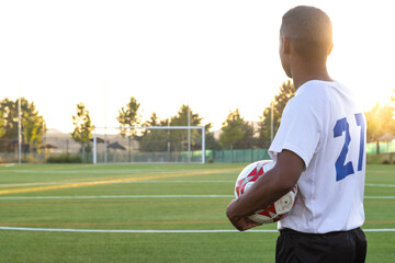 hispanic soccer player in field holding ball in hands