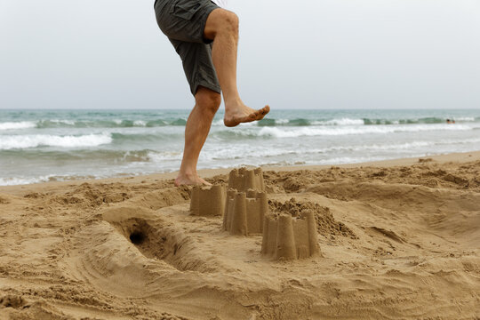 A man destroys sand castles by the sea