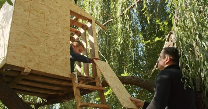 happy father and son building a tree house in the garden