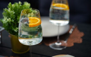 Close-up of two glasses of water with orange. Served table. Flowers. Beautiful interior.