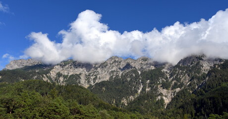 Naklejka na ściany i meble Bergwelt Liechtensteins mit weißen Wolken über dem Bergkamm