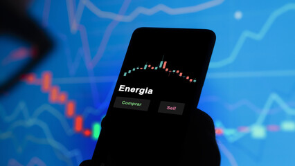Un inversor está analizando el energia etf fondo en pantalla. Un teléfono muestra los precios del ETF para invertir. Texto en español. © maurice norbert