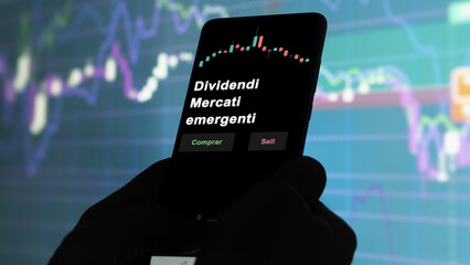 Un inversor está analizando el dividendi mercati emergenti etf fondo en pantalla. Un teléfono...