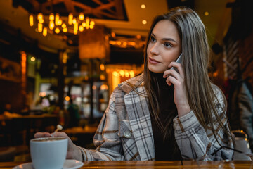 One woman young adult caucasian female sit at cafe alone using mobile phone talk copy space