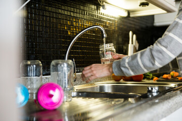 Woman in her kitchen alone at home filling glass of water.