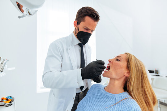 Dentist examining patient's teeth for cavity.