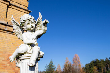The old cemetery. A stone white figure of an angel with wings and arms folded on his chest.