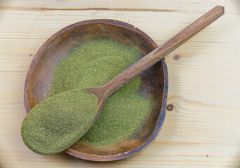 Top view of Kratom powder in wooden bowl and spoon on wooden table, alternative medicine