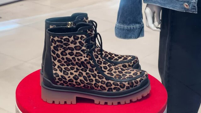 Women's winter fur boots with leopard print stand in the window of a shoe store