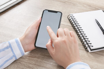 Woman using smartphone at workplace, closeup view