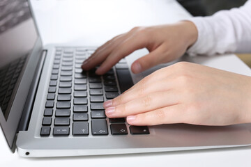 Woman working on laptop at white table in office, closeup