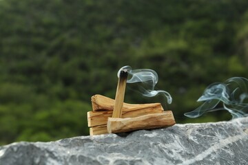 Burning palo santo stick on stone surface outdoors