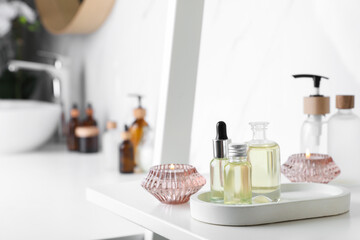 Essential oils and candles on white shelf in bathroom. Space for text