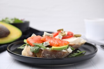 Plate with different tasty bruschettas on white tiled table, closeup