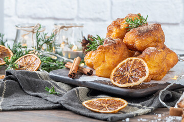 Traditional portuguese Christmas sweets Sonhos with sugar and cinnamon on kitchen countertop.