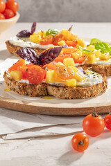 Italian bruschettas with roasted tomatoes, cream cheese, pineapple slices and herbs on a kitchen countertop. Prepared to serve