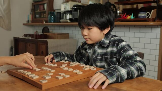 Japanese boy compete Shogi, Japanese chess, against his mother at home.