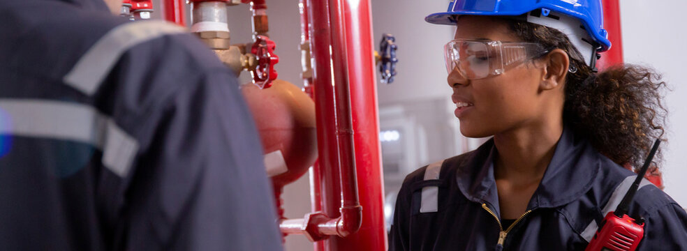 Young woman and man engineer check and examining pipeline and discussion in the factory, mechanic or technician inspector plumber valve and talking together, industrial and maintenance concept.