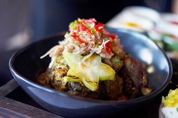 A bowl of bebek betutu (Balinese roast duck) topped with pickled vegetables and sambal at Chandi, a modern fine dining restaurant in Seminyak — Bali, Indonesia