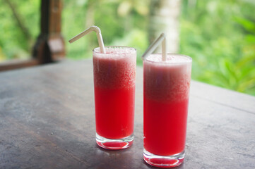 Two glass cups of fresh watermelon juice on a wooden table at a villa in the hills of Ceking, Ubud — Bali, Indonesia