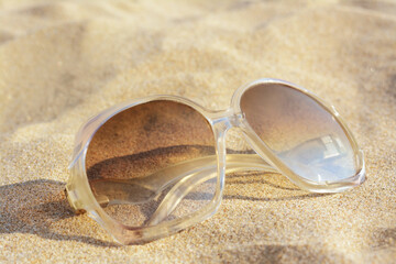 Fototapeta na wymiar Stylish sunglasses on sandy beach, closeup view